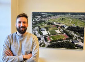 Jussi Yli-Renko Salon Urheilupuistosta otetun ilmakuvan vieressä. Kuvan ottohetki tarkentuu viikon tarkkuudella, sillä vasemmassa ylälaidassa erottuu Salo Jukolan vuoden 2006 kilpailualue Karjaskylässä telttoineen ja lähtöviitoituksineen.