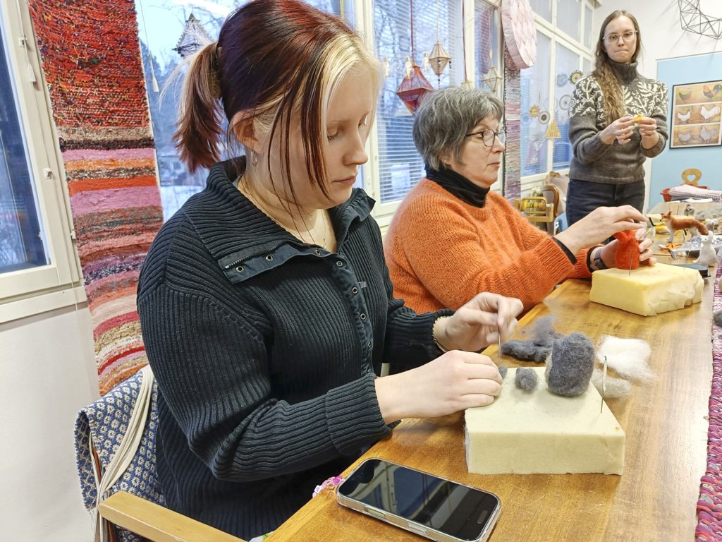 Helmi Tanninen huovuttaa Totoro-hahmon. Hänen vieressään Maarit Järvinen valitsi työnsä värin sattumalta samassa sävyssä kuin paitansa.
