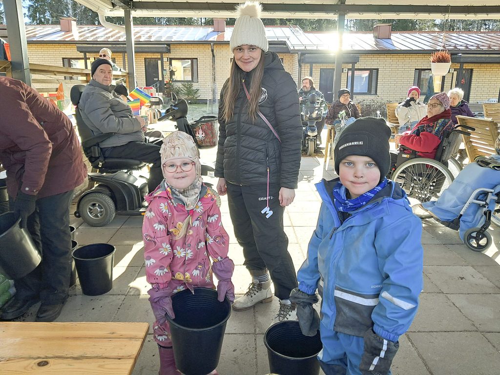 Onni Mäkitalo (oik.) ja Misla Lamppu istuttavat perunoita. -Mä en syö noita, vaan niiden pitää ensin kasvaa, tietää Misla. Keskellä Pihlajakylän ohjaaja Marjukka Lamppu.